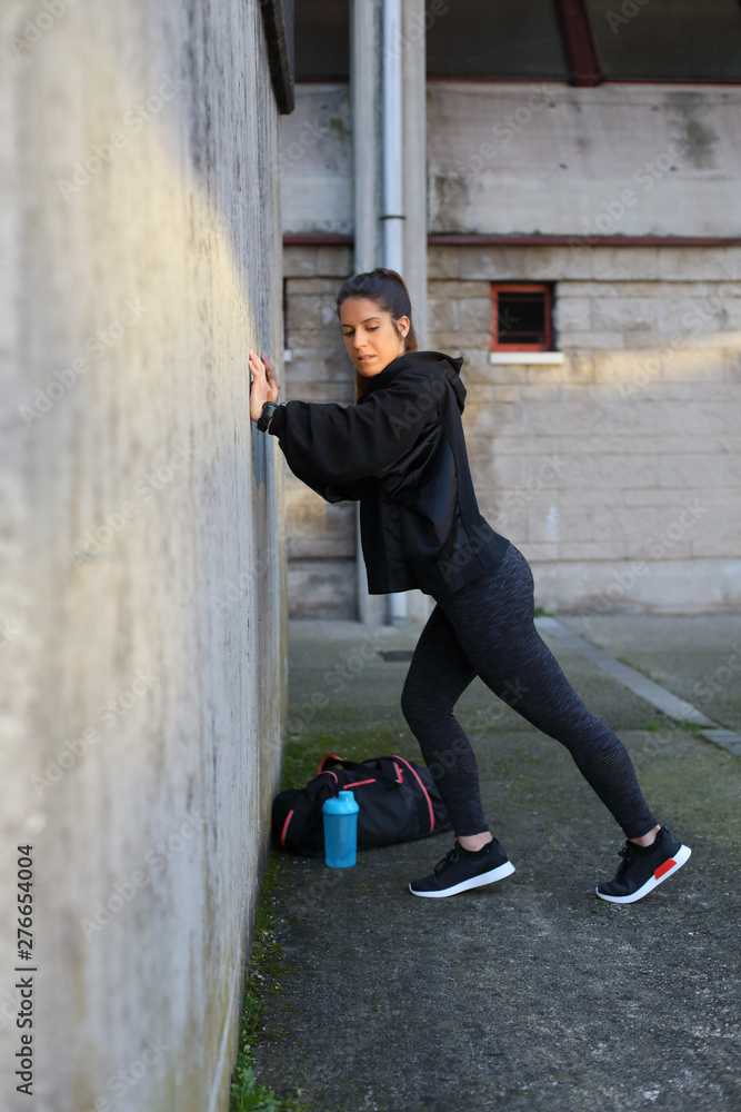 Sporty young woman doing calf stretching exercise for warming up before fitness urban workout. Sporty young woman doing calf stretching exercise for warming up before fitness urban workout.