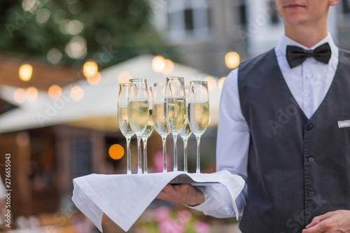 Catering service waiter holding a tray with glasses of Italian and French wine prosecco and champagne for tasting