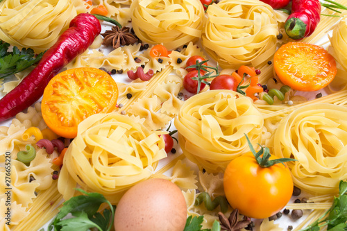 Italian pasta of various kinds with spices, red hot pepper, chicken eggs, yellow and red tomatoes on a white background. Concept cooking Italian pasta and sauce