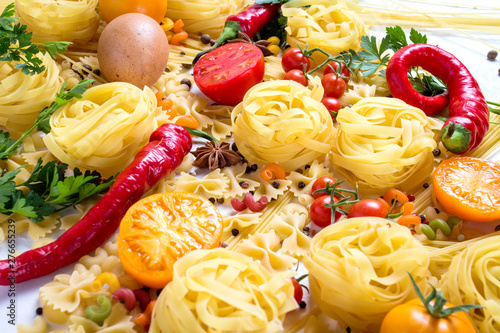 Italian pasta of various kinds with spices, red hot pepper, chicken eggs, yellow and red tomatoes on a white background