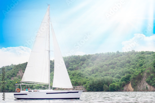 Sailboat in the sea in the sunnt day over beautiful big mountains background, luxury summer adventure, active vacation . Space for text