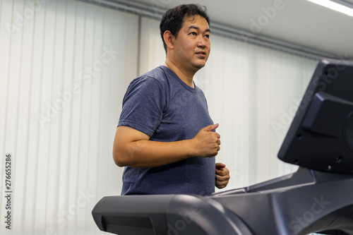 Male adult athletes are running on the equipment right machine treadmill are an indoor exercise at the gym after work, making the body healthy and happy.