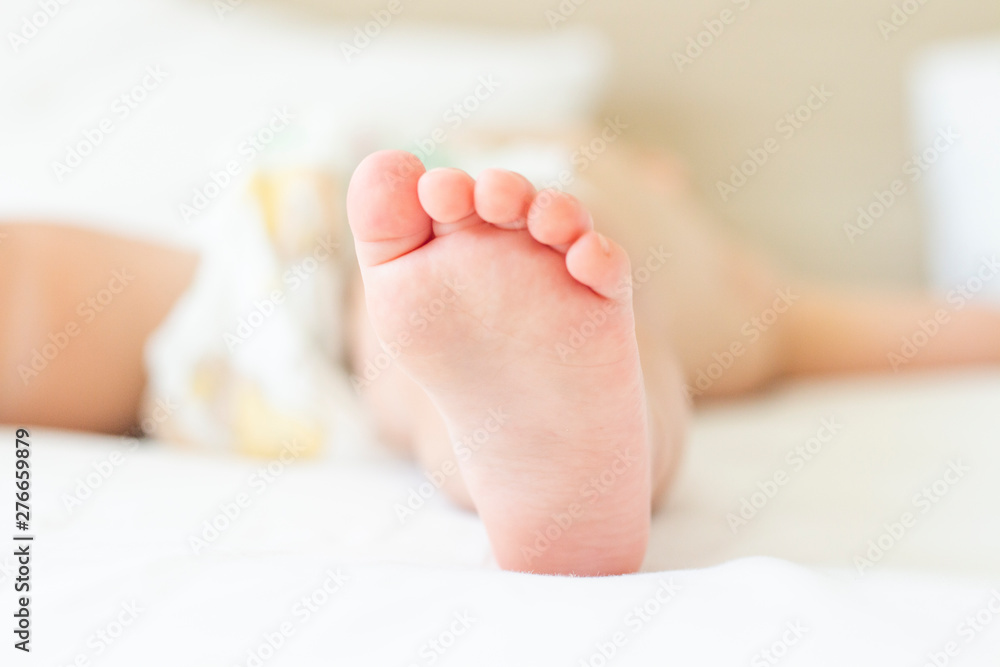 Leg of a sleeping child in bed with white sheets. Concept of a good and sound baby sleep Leg of a sleeping child in bed with white sheets. Concept of a good and sound baby sleep