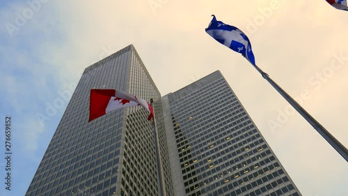 Low angle shot of a high skyscraper tower (place Ville-Marie, Montreal), canada and Quebec flags and beautiful sky and clouds. photo