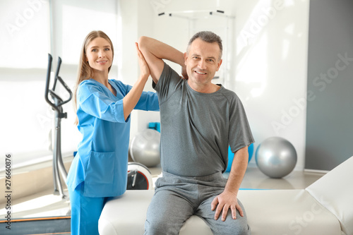 Physiotherapist working with mature patient in rehabilitation center photo