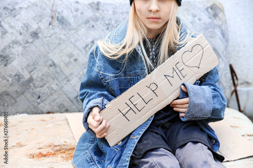 Homeless little girl begging for help outdoors photo