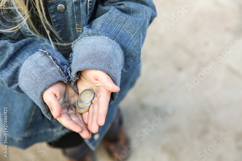 Homeless little girl with coins outdoors photo