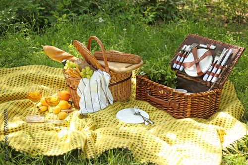 Fototapeta Naklejka Na Ścianę i Meble -  Wicker baskets with tasty food and drink for romantic picnic in park