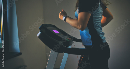The young woman does workout time on her treadmill in home