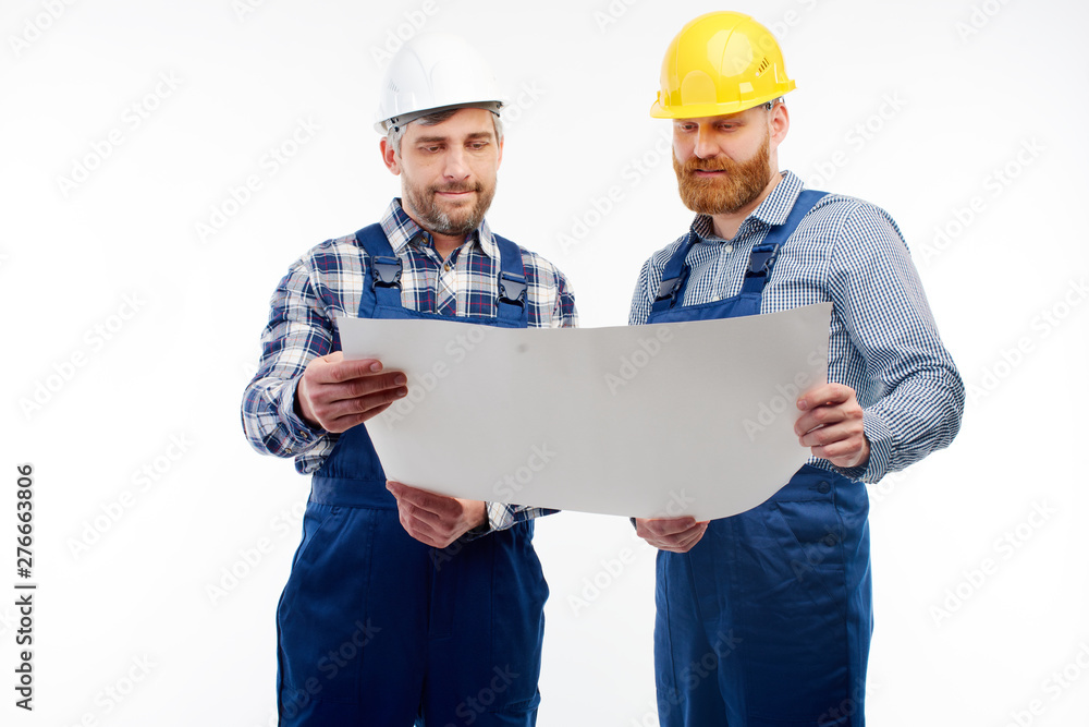 Two engineers are discussing a new project looking at the blueprints. Two engineers are discussing a new project looking at the blueprints.