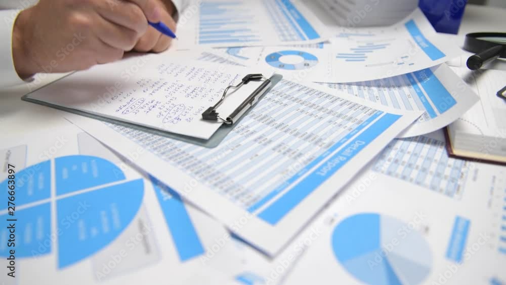 Businessman working and calculating, reads and writes reports. Office employee, table closeup. Business financial accounting concept. Businessman working and calculating, reads and writes reports. Office employee, table closeup. Business financial accounting concept.