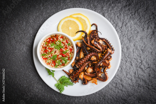 Octopus salad with lemon herbs and spices on white plate / Tentacles squid grilled appetizer food hot and spicy chilli sauce seafood cooked