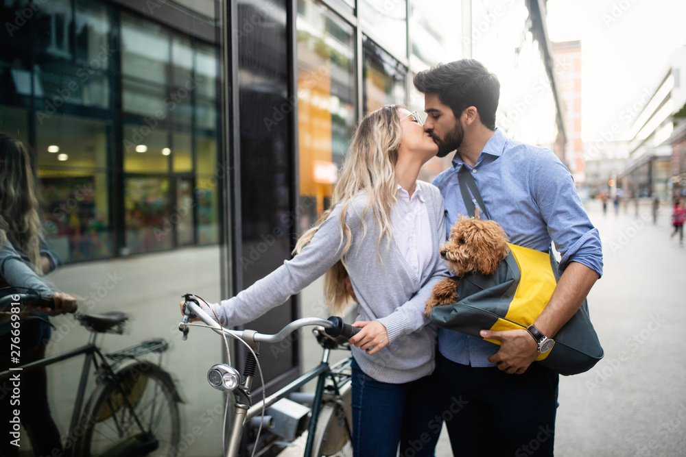Beautiful couple walking dogs and bicycles outdoors in city