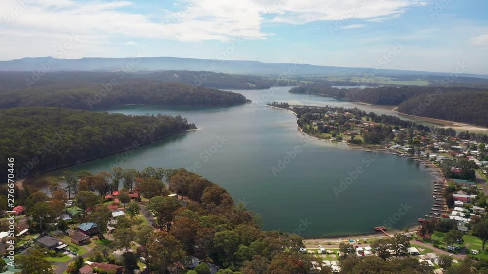 Aerial, tracking, drone shot, overlooking forest, beaches, a town and nature, on the coast of Burrill lake, on a sunny day, in New South Wales, Australia Aerial, tracking, drone shot, overlooking forest, beaches, a town and nature, on the coast of Burrill lake, on a sunny day, in New South Wales, Australia