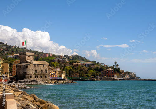 Scenic view of the bay of Rapallo in the Ligurian Riviera with the stone castle (1551) on the rocky beach and the coastline in the background in a sunny day with blue sky, Genoa, Italy