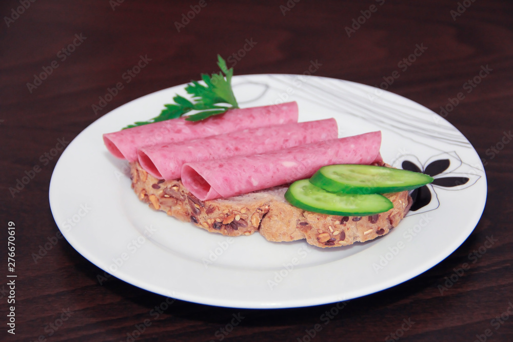 sandwich of rye bread with meat sausage, cucumbers and parsley