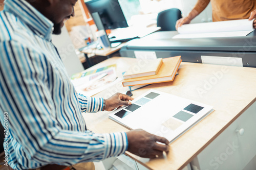 Top view of dark-skinned man choosing color for book cover