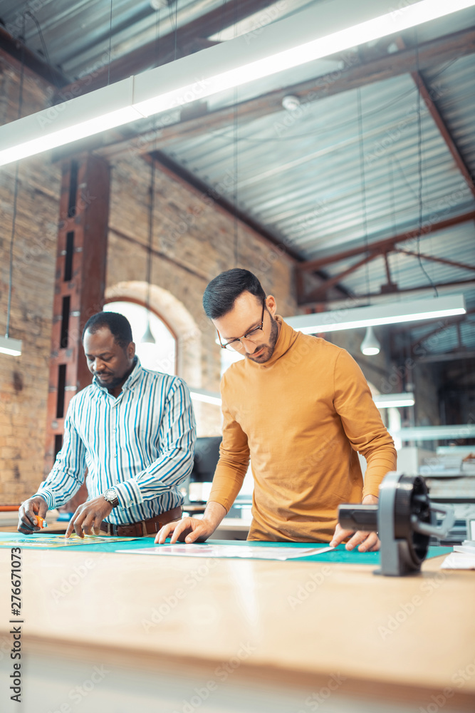 Bearded man wearing glasses helping graphic designer Bearded man wearing glasses helping graphic designer