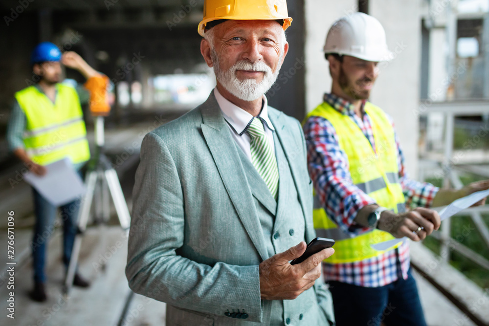 Confident construction engineer, architect, businessman in hardhat on building site Confident construction engineer, architect, businessman in hardhat on building site