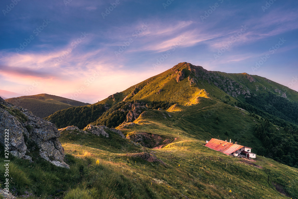 Idyllic landscape in the Old mountain, Central Balkan national park in Bulgaria. Eho hut surrounded with fresh green mountain pastures with blooming flowers in beautiful morning light at sunrise