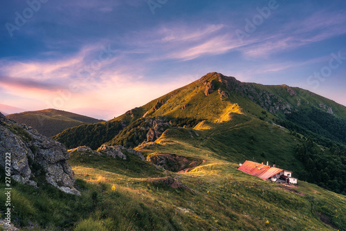 Idyllic landscape in the Old mountain, Central Balkan national park in Bulgaria. Eho hut surrounded with fresh green mountain pastures with blooming flowers in beautiful morning light at sunrise