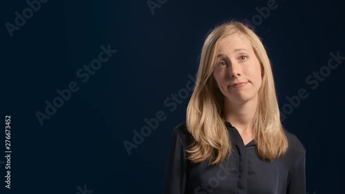 Portrait of an indifferent undecided blond woman  shrugging her shoulders making a clueless face
