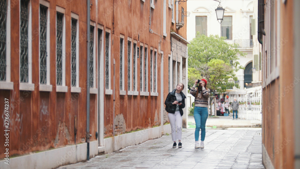 Two young women travelers walking on the narrow streets of Venice, Italy