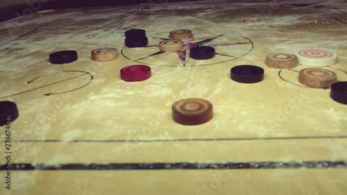 carom board coins hit by striker. all coins moving along with striker photo