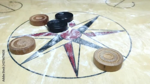 carom board coins hit by striker. all coins moving along with striker photo