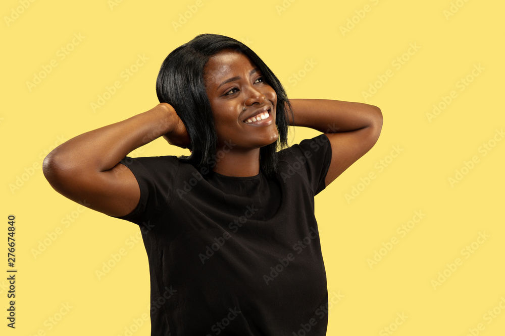 Young african-american woman isolated on yellow studio background, facial expression. Beautiful female half-length portrait. Concept of human emotions, facial expression. Resting and smiling. Young african-american woman isolated on yellow studio background, facial expression. Beautiful female half-length portrait. Concept of human emotions, facial expression. Resting and smiling.