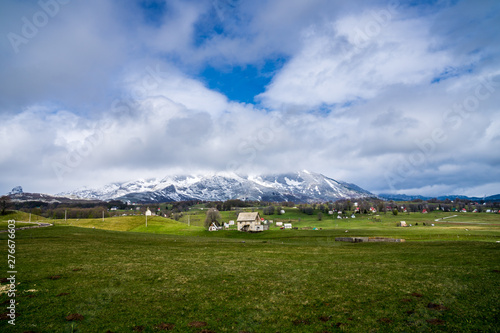 Montenegro, Houses and trees on green meadow next to snow covered mountains of durmitor national park nature landscape near town provalija photo