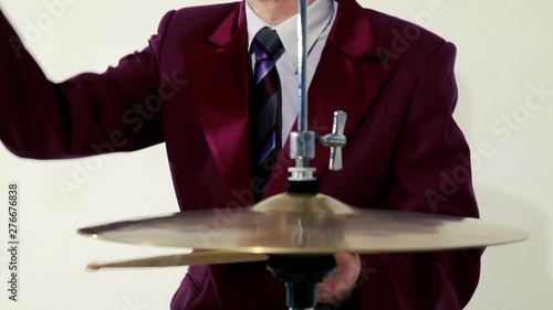 Drummer in a purple jacket and striped tie expressively playing drumsticks on hi-hat close up