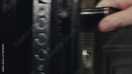 door handle turning, door opening, a man in a black leather jacket goes out, and close the door lock with a key, close up