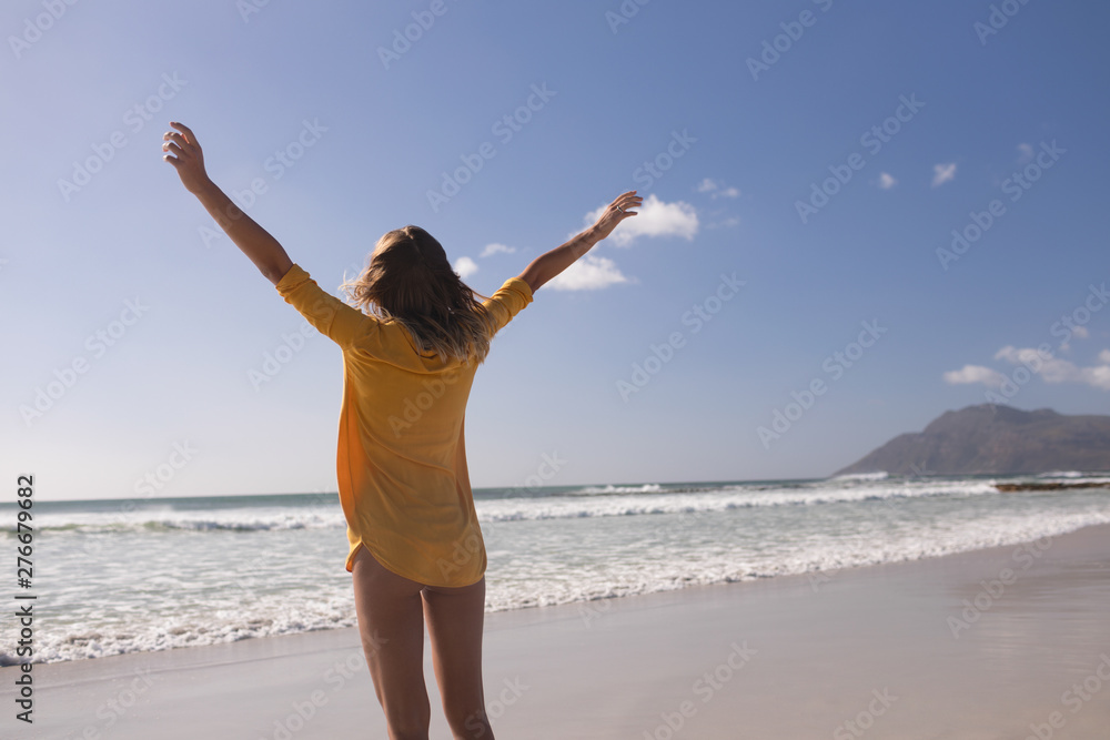 Woman standing with arms outstretched at beach Woman standing with arms outstretched at beach