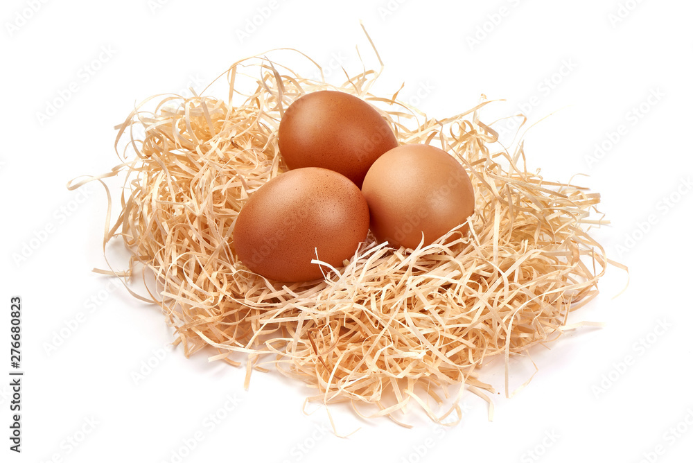 Chicken eggs in a straw nest, close-up, isolated on white background Chicken eggs in a straw nest, close-up, isolated on white background