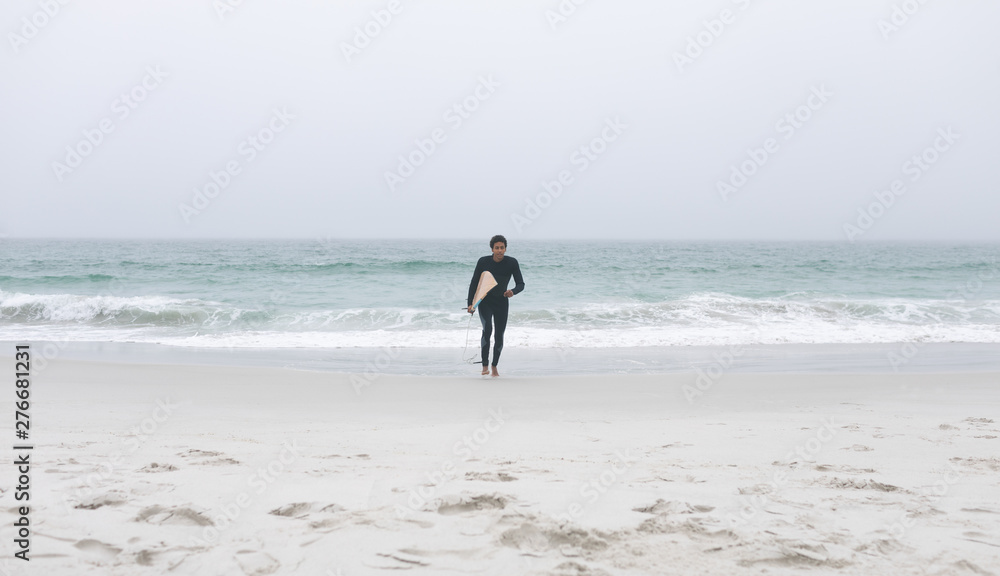 Male surfer running on the beach with surfboard Male surfer running on the beach with surfboard