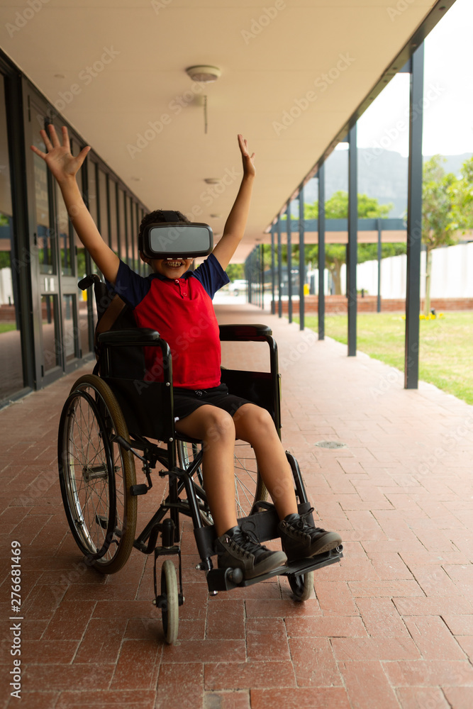 Obraz premium Happy disabled schoolboy using virtual reality headset in corridor
