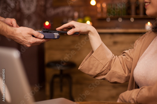 Hand of customer paying with contactless mobile phone technology in a coffee shop