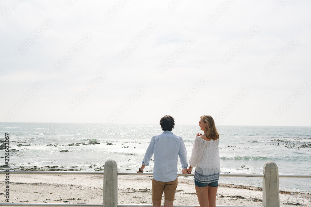 Caucasian couple standing near sea side at promenade on a sunny day