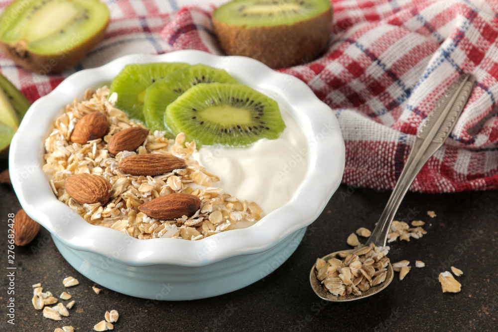 Greek white yogurt with kiwi almonds and oatmeal on a dark brown table. breakfast. healthy food Greek white yogurt with kiwi almonds and oatmeal on a dark brown table. breakfast. healthy food