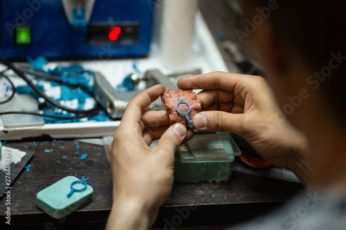 Close-up of an experienced jeweler pulls out a blank silicone ring to make a diamond ring in the workshop.