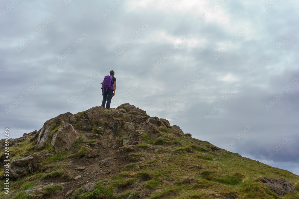 Hiker standing on the mountain peak at The Storr Trail , Isle of Skye , Scotland