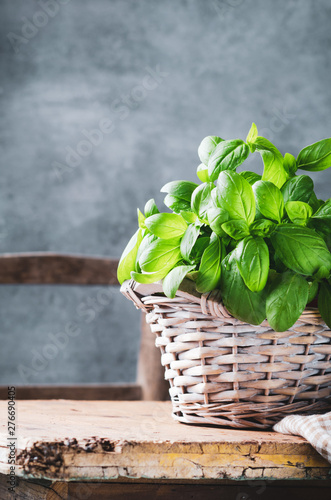 Pesto sauce in a olive wooden bowl with pine nuts, basil, parmesan and garlic over rustic table.