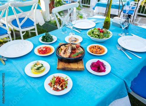 Shrimp, Seafoods, appetizers and salads on the table in Fish Restaurant. Beach Restaurant in Greece or Turkey. Aegean seaside, Greek or Turkish style fish restaurant in Bodrum, Santorini or Mykonos