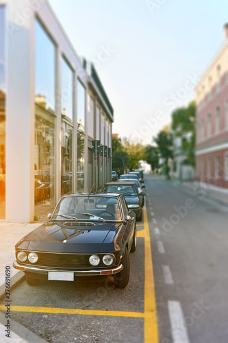 street with parked old cars in perspective, blurred background, cityscape