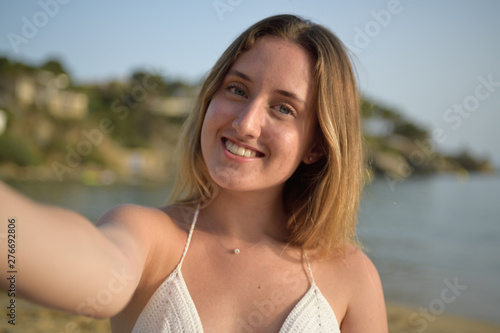 Close up portrait of a girl smiling and taking selfie on the beach