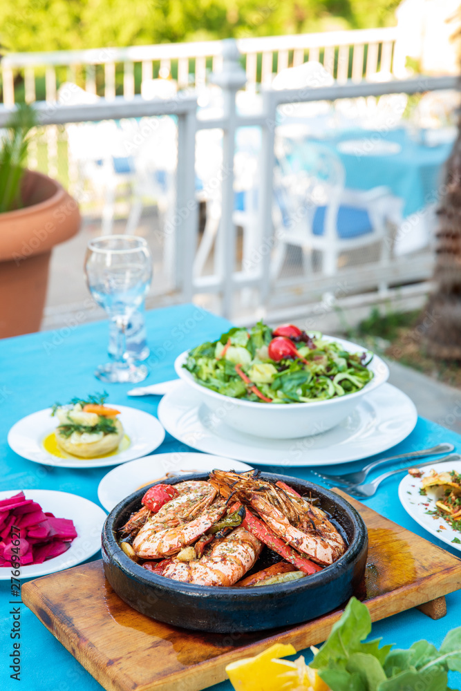 Shrimp, Seafoods, appetizers and salads on the table in Fish Restaurant. Beach Restaurant in Greece or Turkey. Aegean seaside, Greek or Turkish style fish restaurant in Bodrum, Santorini or Mykonos