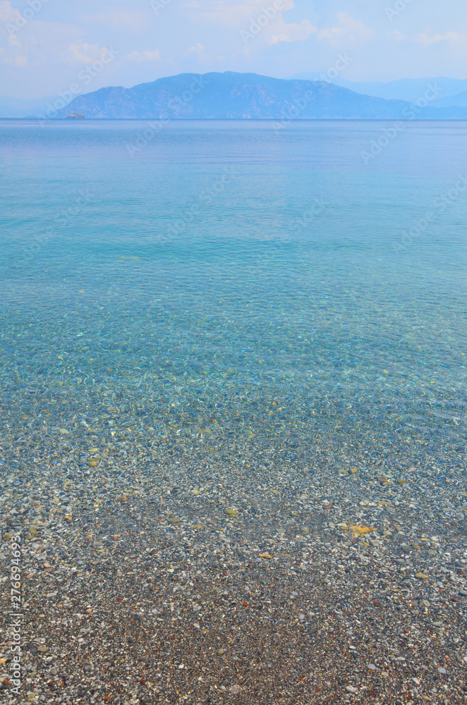 Sea landscape with pebbles and island in Turunc, Turunch Kumlubuk Mugla