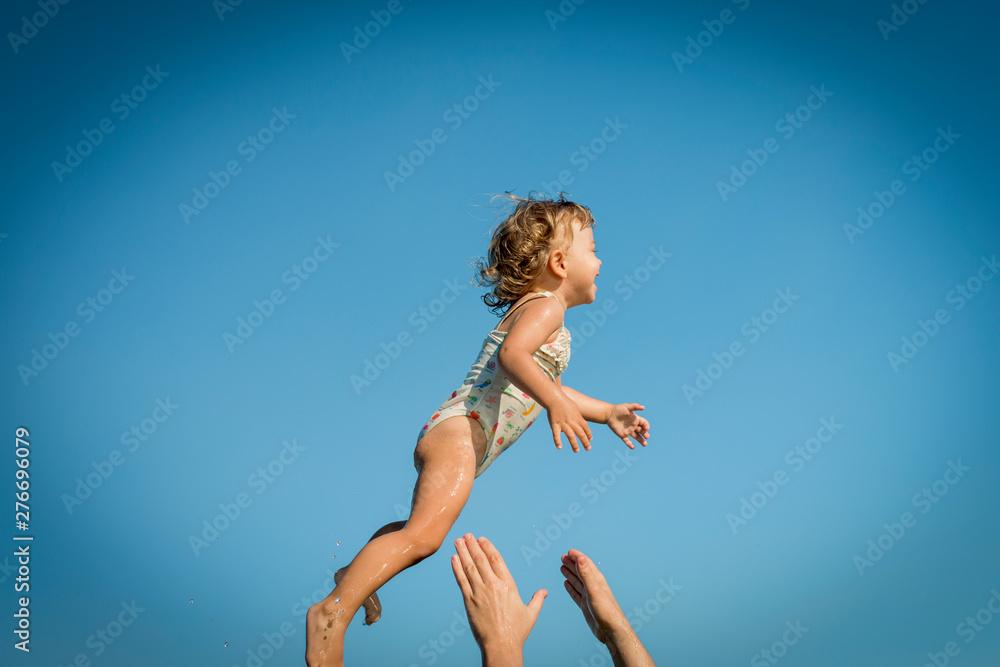 little girl flies through the air and daddy's hands