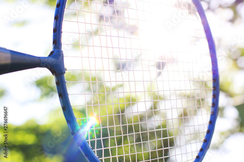 Badminton racket close up against a background of trees